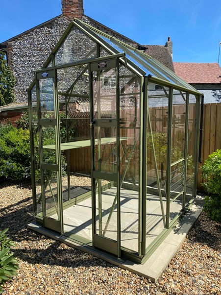 <strong>DELTA:</strong> A 5’3 (1590mm) wide model in lengths from 4’5 (1351mm) onwards. It is compact in size but has tall eaves of 5’8 (1726mm) and double doors which provide an opening of 6’3 x 2’ (1910mm x 600mm) ensuring a good working space. Pictured is an Elite Delta 5ft 3in x 6ft 4in ‘Olive” colour finish with staging, shelf, Louvre vent, auto roof vent, rain kit and bar capping. 5ft 8in high side walls give spacious feel to these greenhouses.